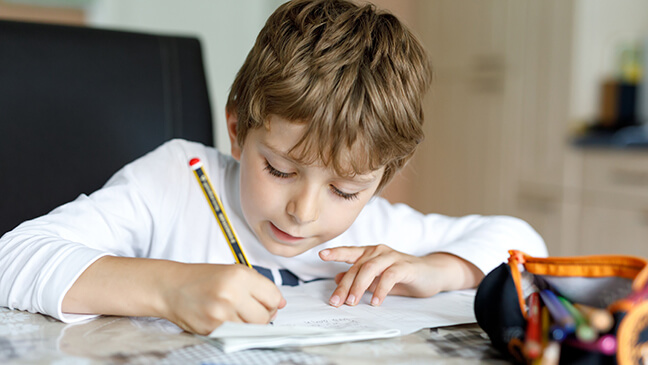 Jongen maakt huiswerk aan tafel