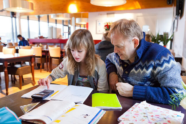 Ouderparticipatie: Vader begeleid dochter met huiswerk in de huiswerkklas