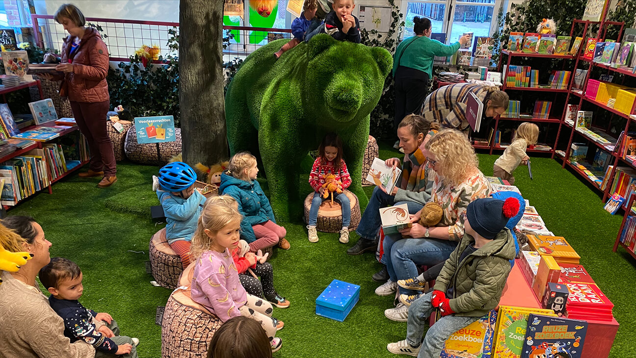 vrouw leest voor aan kinderen in kinderboekenwinkel pardoes