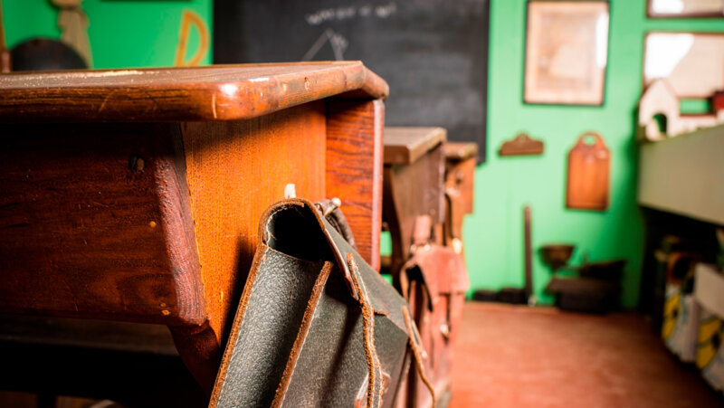 Oude schoolbanken en boekentas in het heem