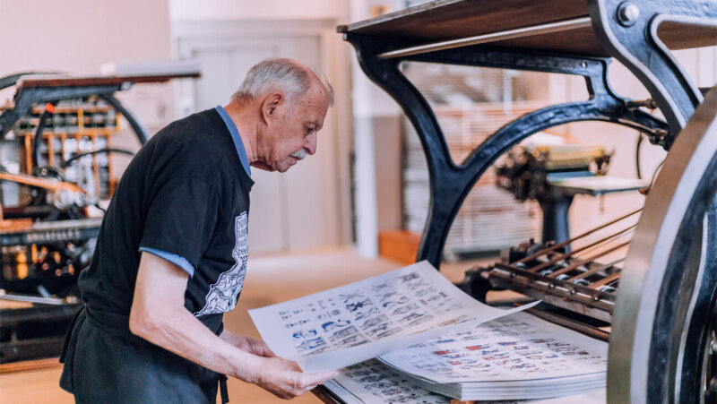 Man aan een drukpers in de drukkerij van het nationaal museum van de speelkaart