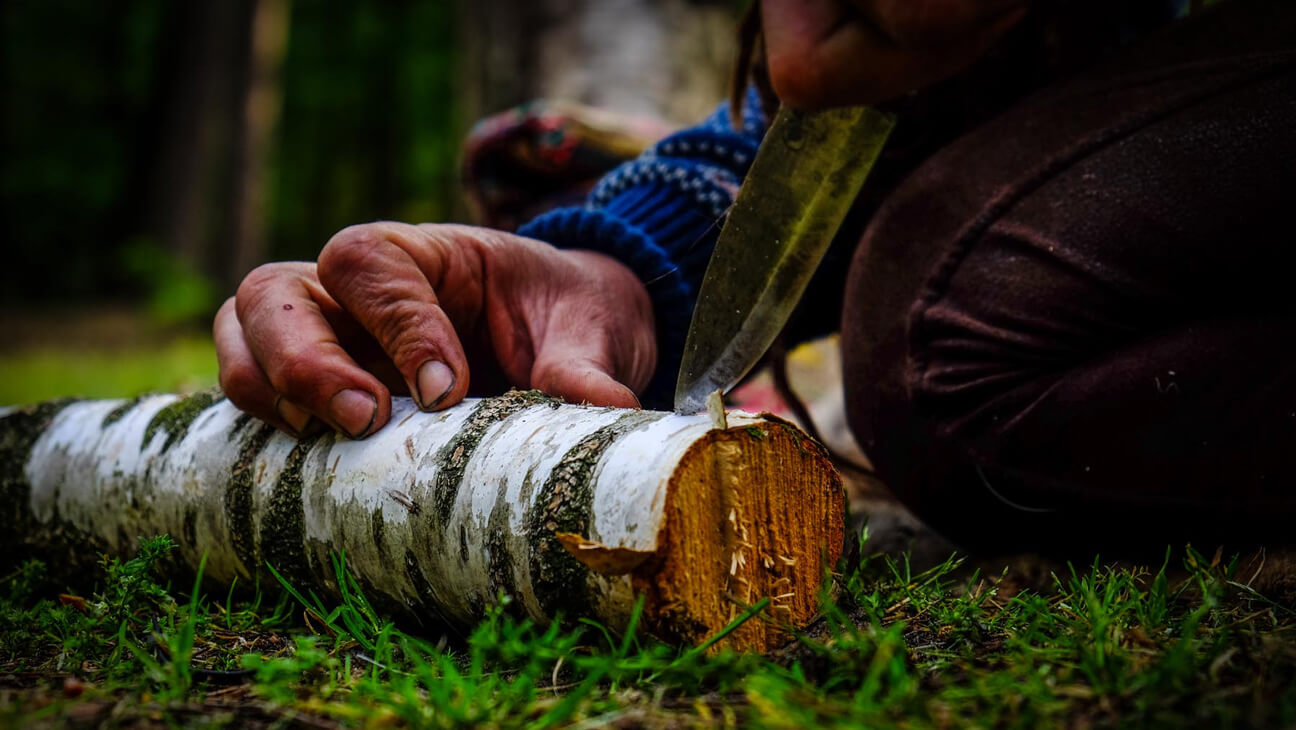 Mes in houtblok tijdens opleiding van Outdoorschool