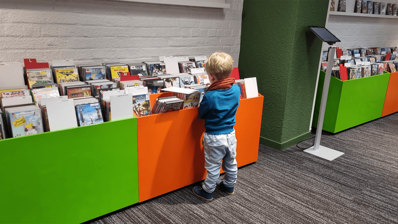 Jongen zoekt boek in rek