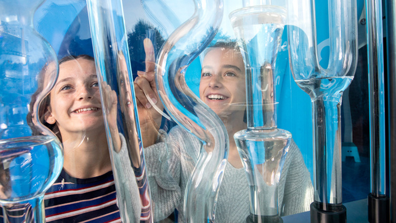 2 meisjes kijken enthousiast naar buizen met water