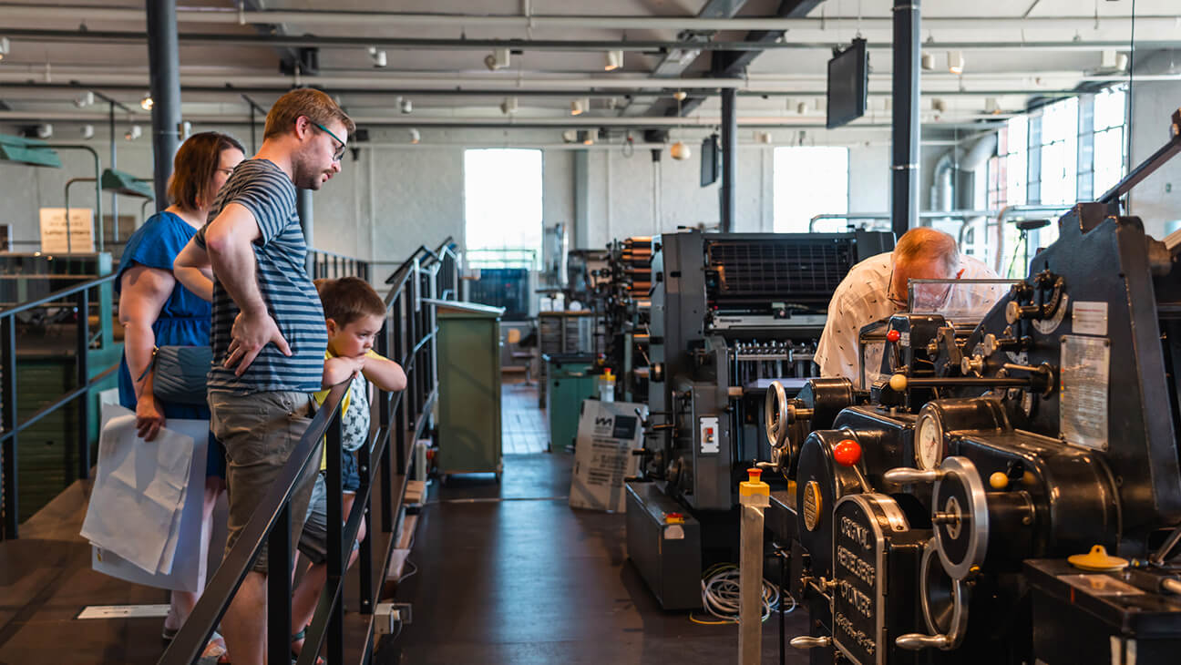 bezoekers kijken naar een oude drukpers in het industriemuseum