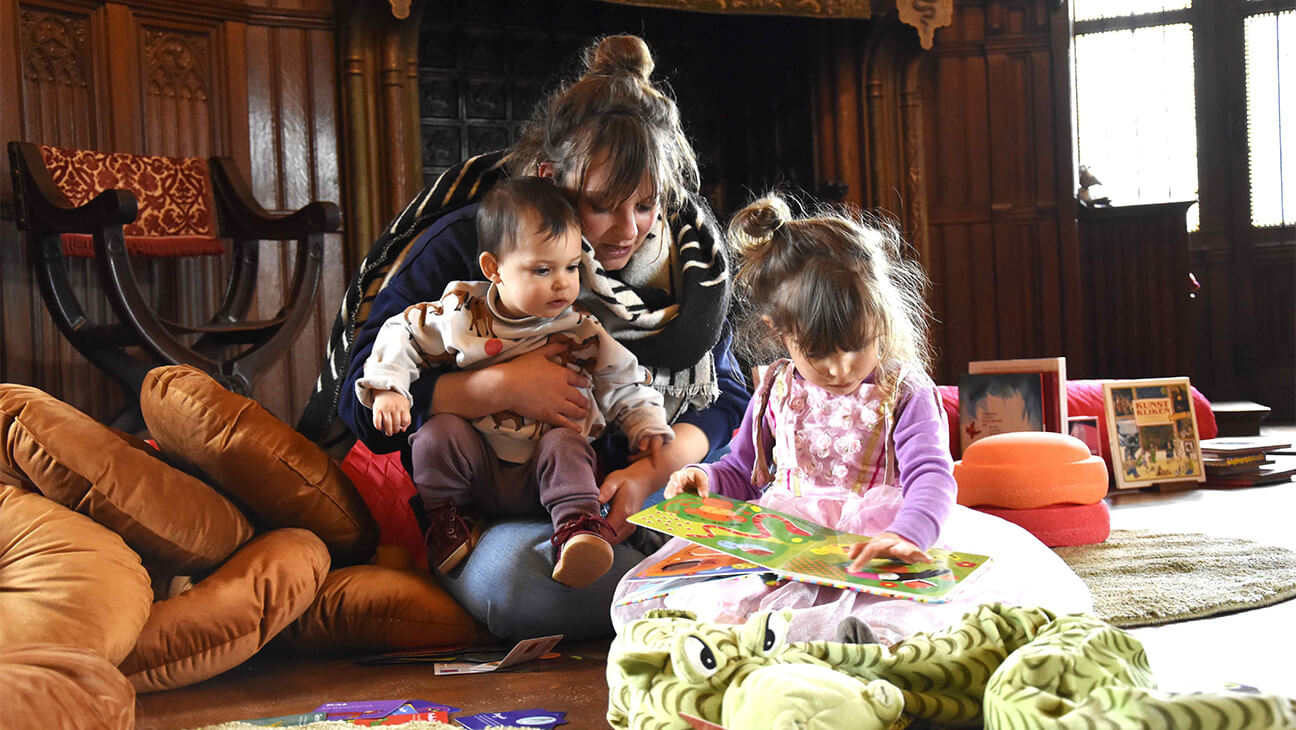 Vrouw met 2 kindjes lezen een boek in het kasteel van Gaasbeek