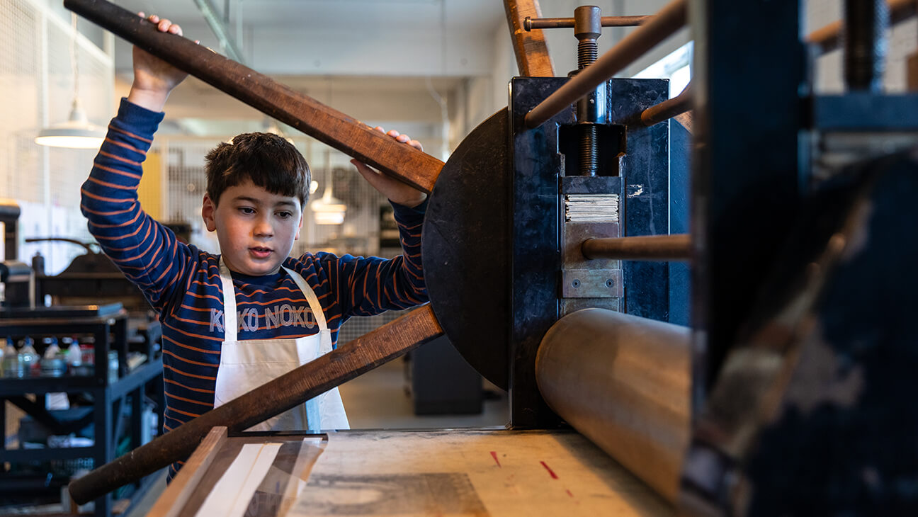 Kind aan de historische drukpers in het speelkaartenmuseum