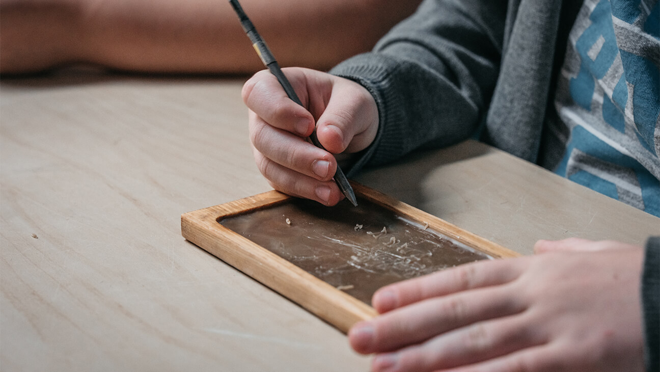 Kind tekent op een oud krijtbordje
