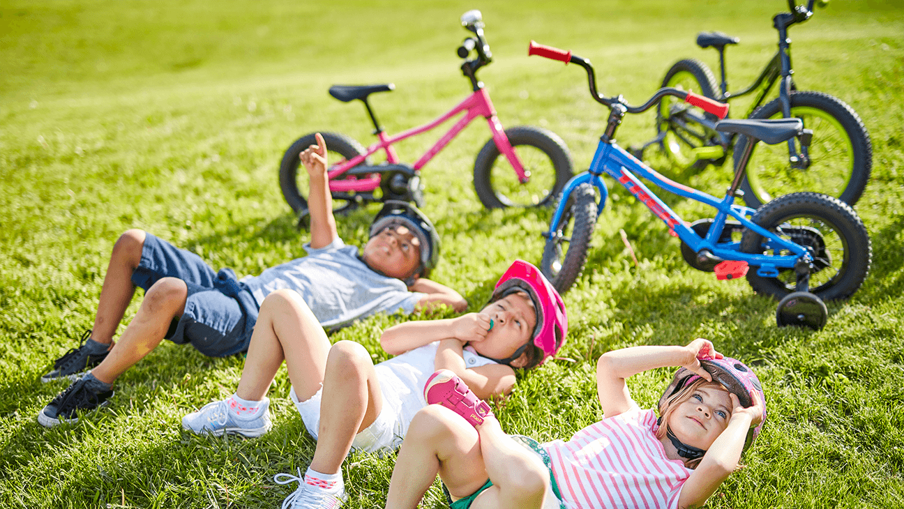 3 kinderen in grasveld met fiets