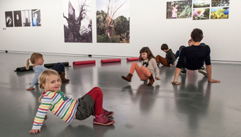 Een groep je kinderen lopen op handen en voeten door het Fotomuseum