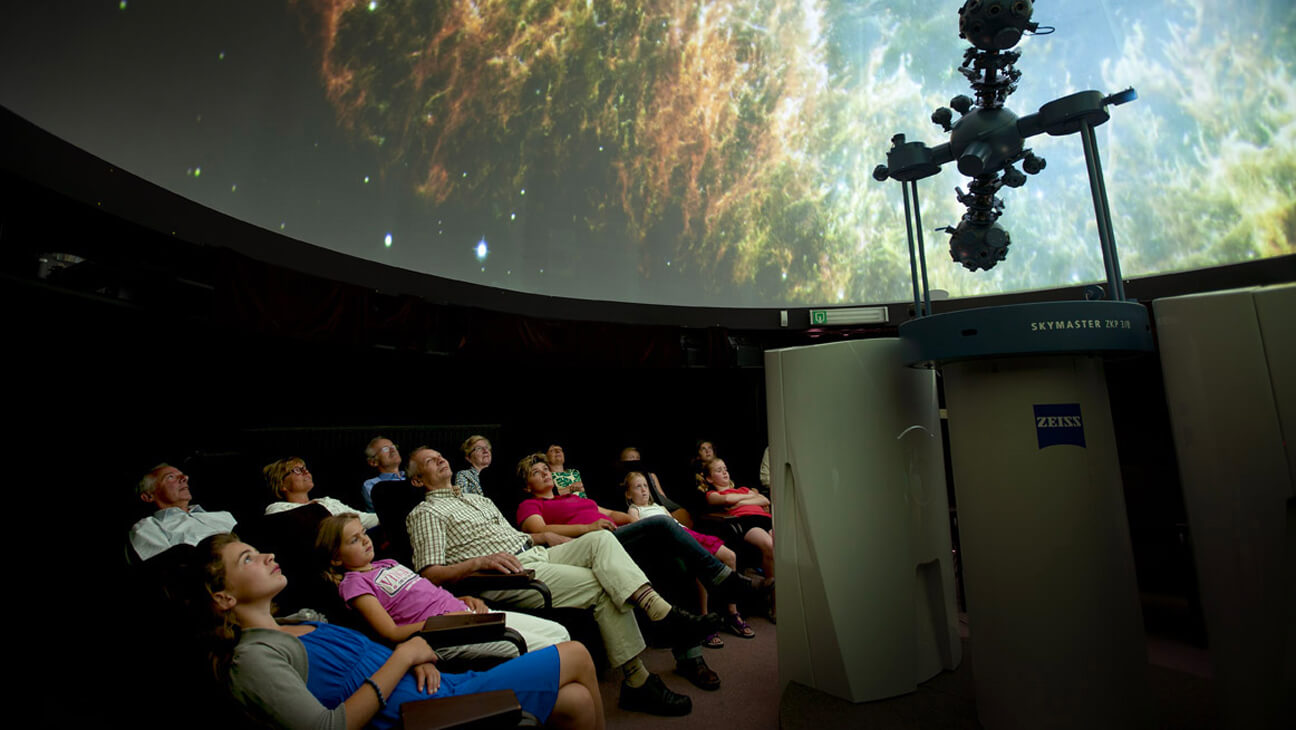 Mensen kijken naar sterrenhemel in het planetarium