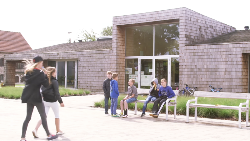 Jongens zitten op bankje voor schoolgebouw