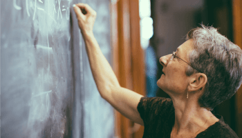 Vrouwelijke leraar schrijft formule in krijt op bord
