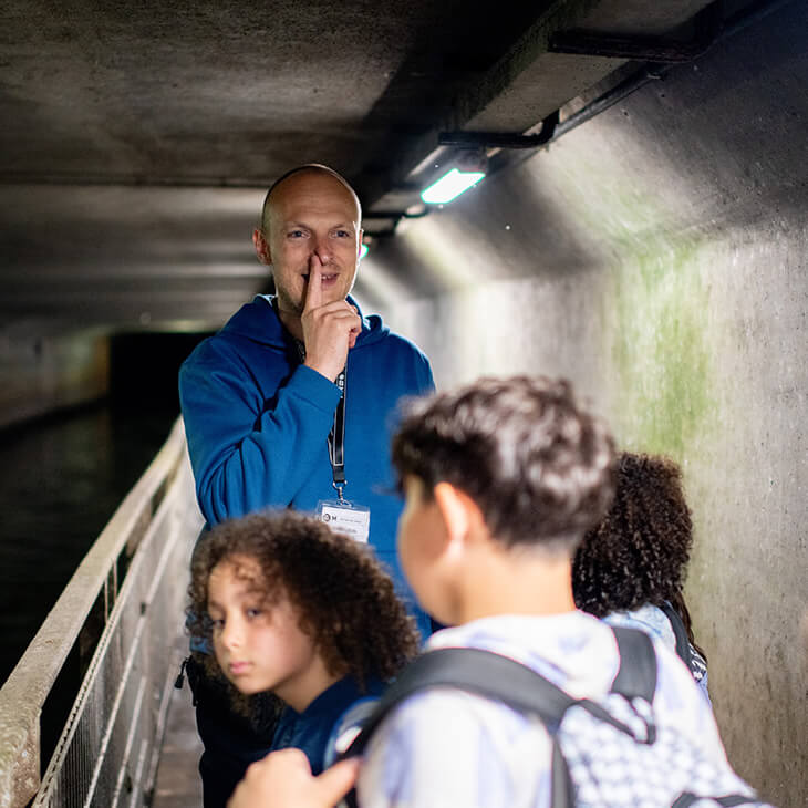 Gids wijst naar neus in het Riolenmuseum in Brussel