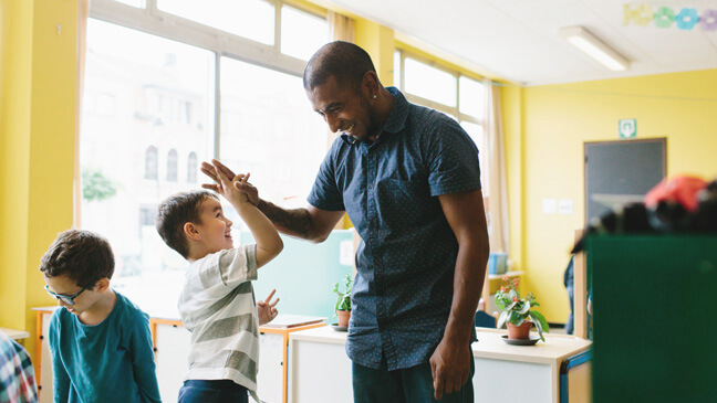 Leraar Mathew geeft high five aan leerling