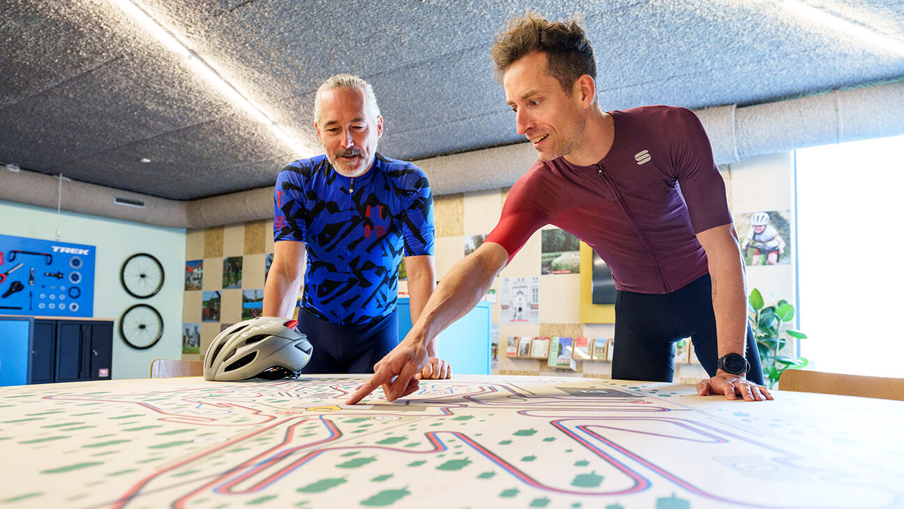 2 mannen bij een map van het Sven Nys Cycling Center