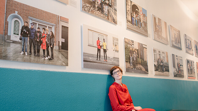 Katrien Demaeght in de gang van de school met het fotoproject aan de muren