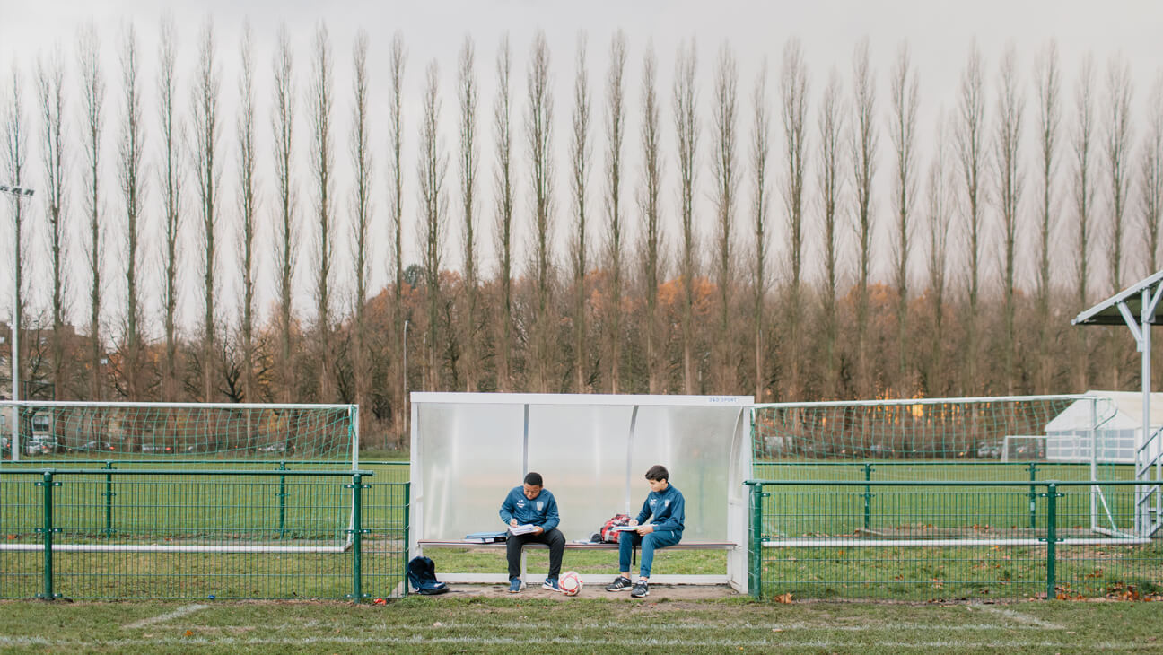 Samuel en Si Mohamed maken voor de training hun huiswerk.