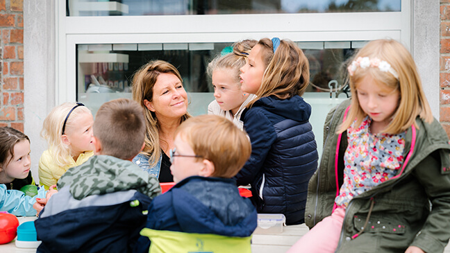 directeur Rebekka Buyse tussen haar leerlingen op de speelplaats