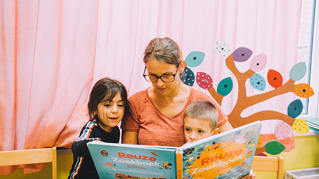 Juf Hanne leest boek met 2 leerlingen