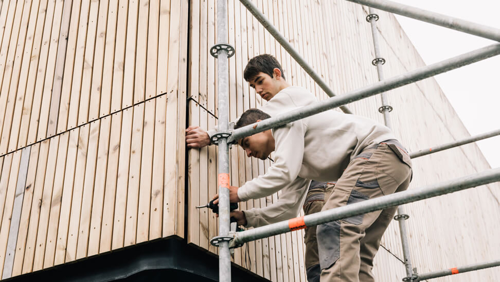 STEM-school: leerlingen plaatsen houten latten tegen de gevel van het gebouw