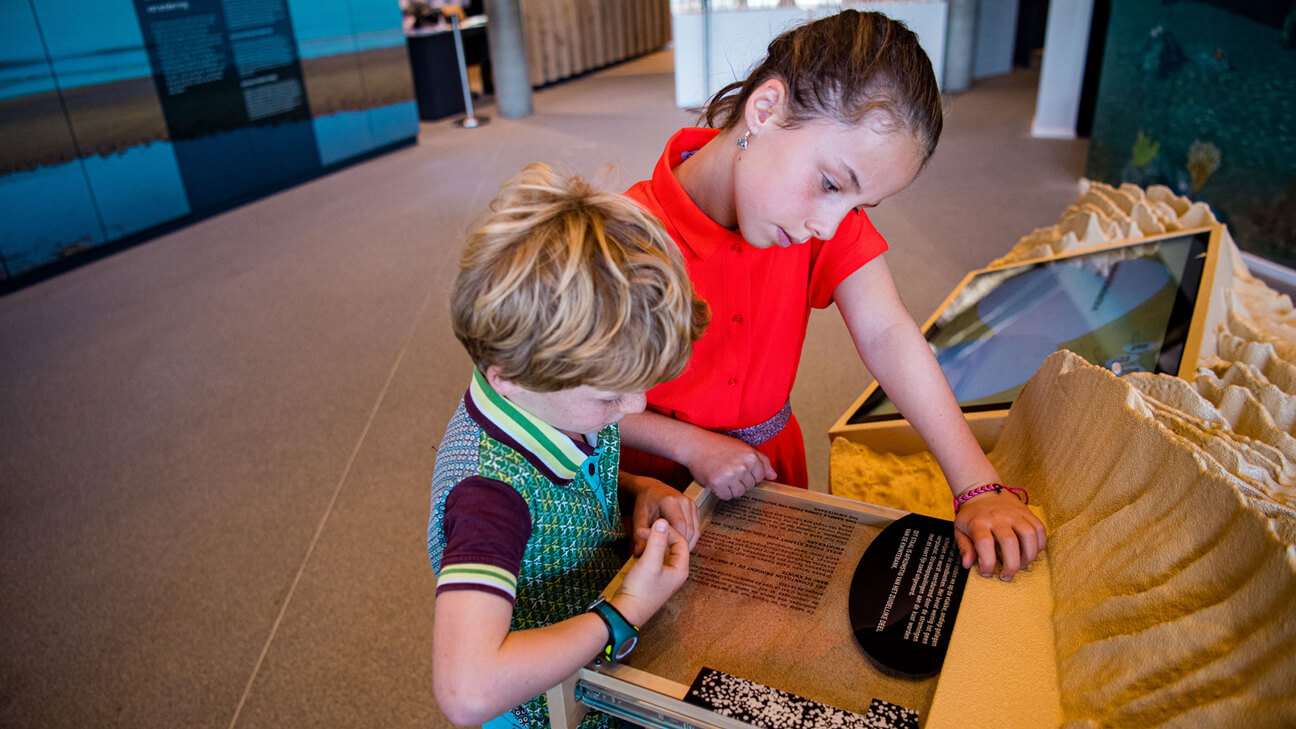 Broer en zus lezen infobord van expo Sea Change