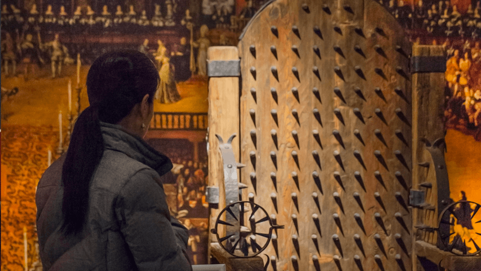 bezoeker aan het torture museum naast een foltertuig