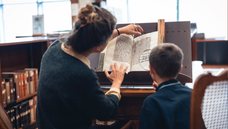 Vrouw toont middeleeuws boek aan kind