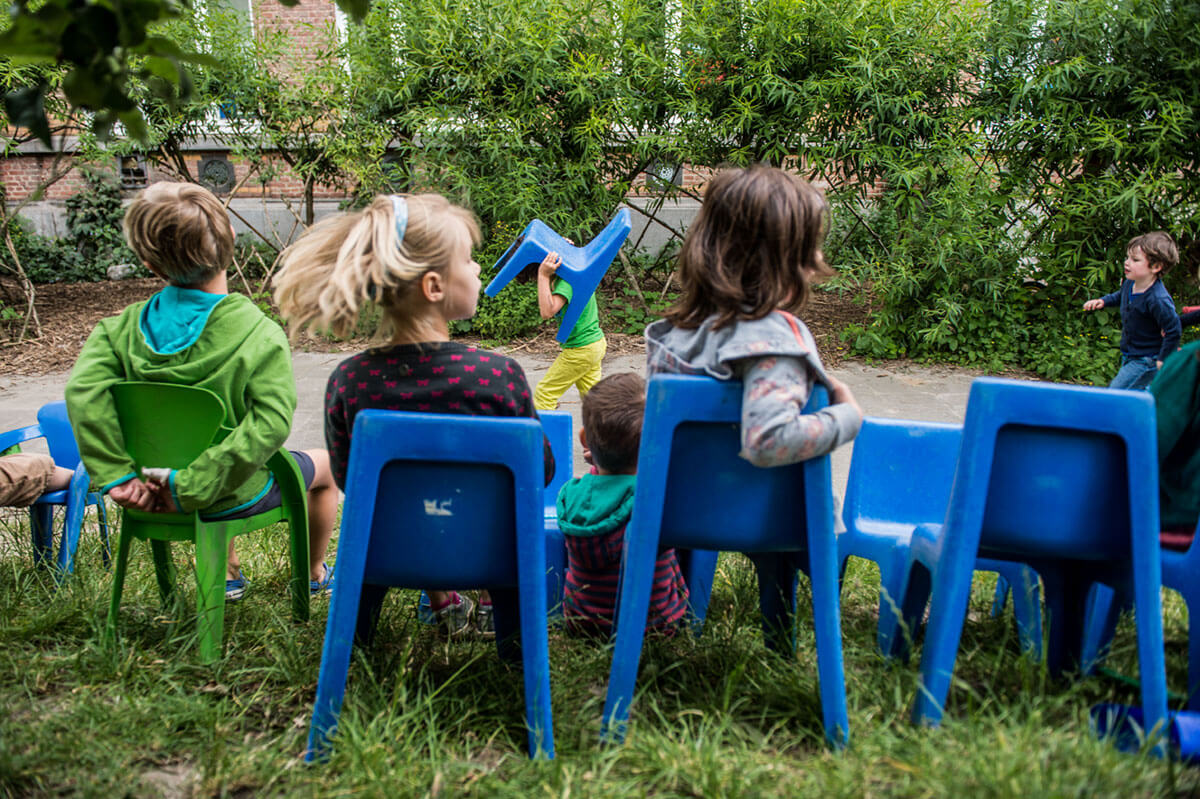 Kinderen zitten op blauwe stoeltjes