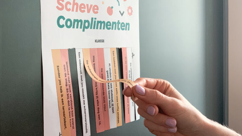 hand scheurt strookje met compliment af van scheurposter met scheve complimenten