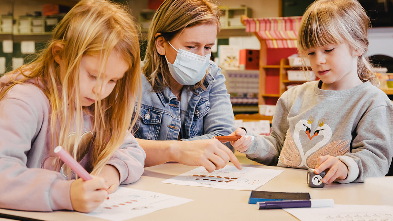 Leraar Griet in haar klas met 2 leerlingen