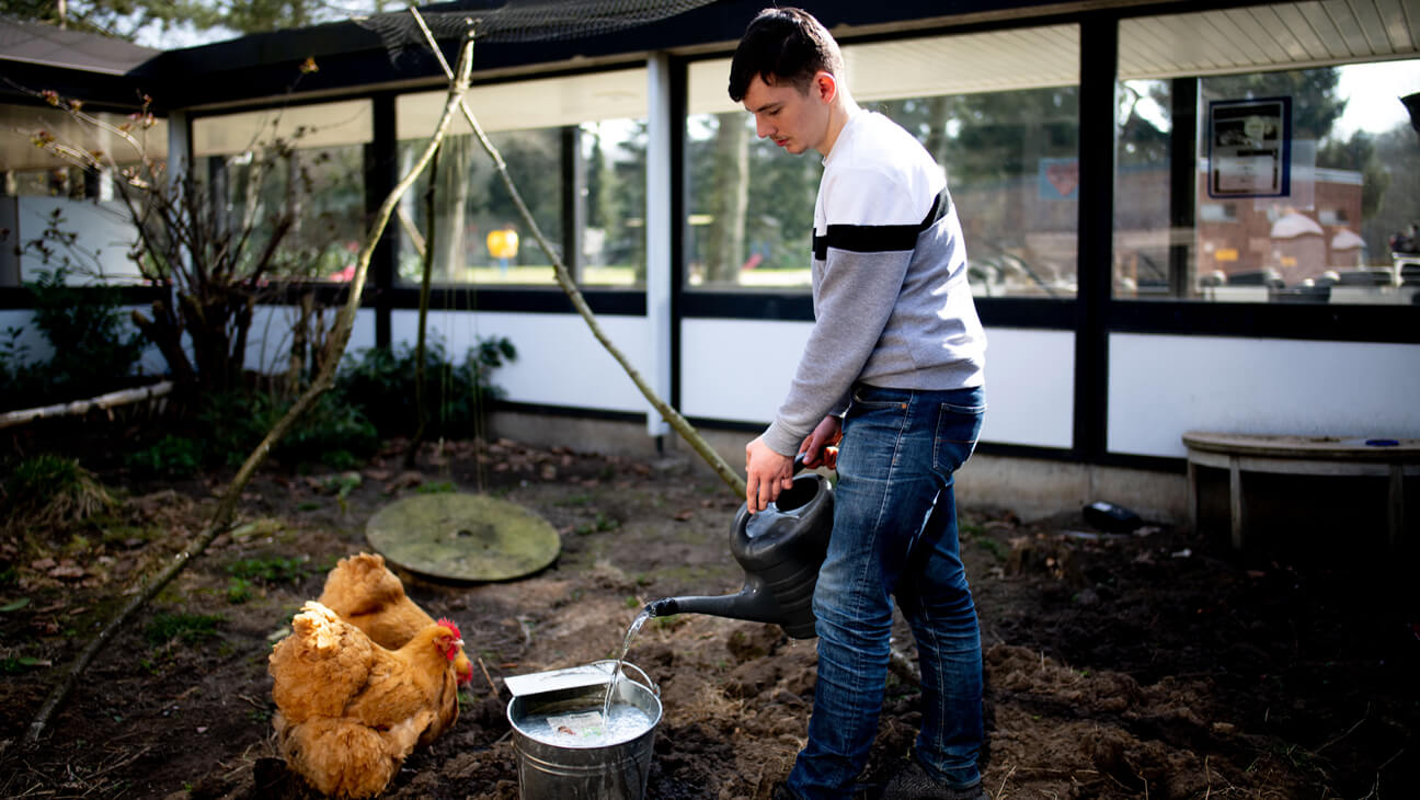 Leerling giet schooltuin met opgevangen regenwater