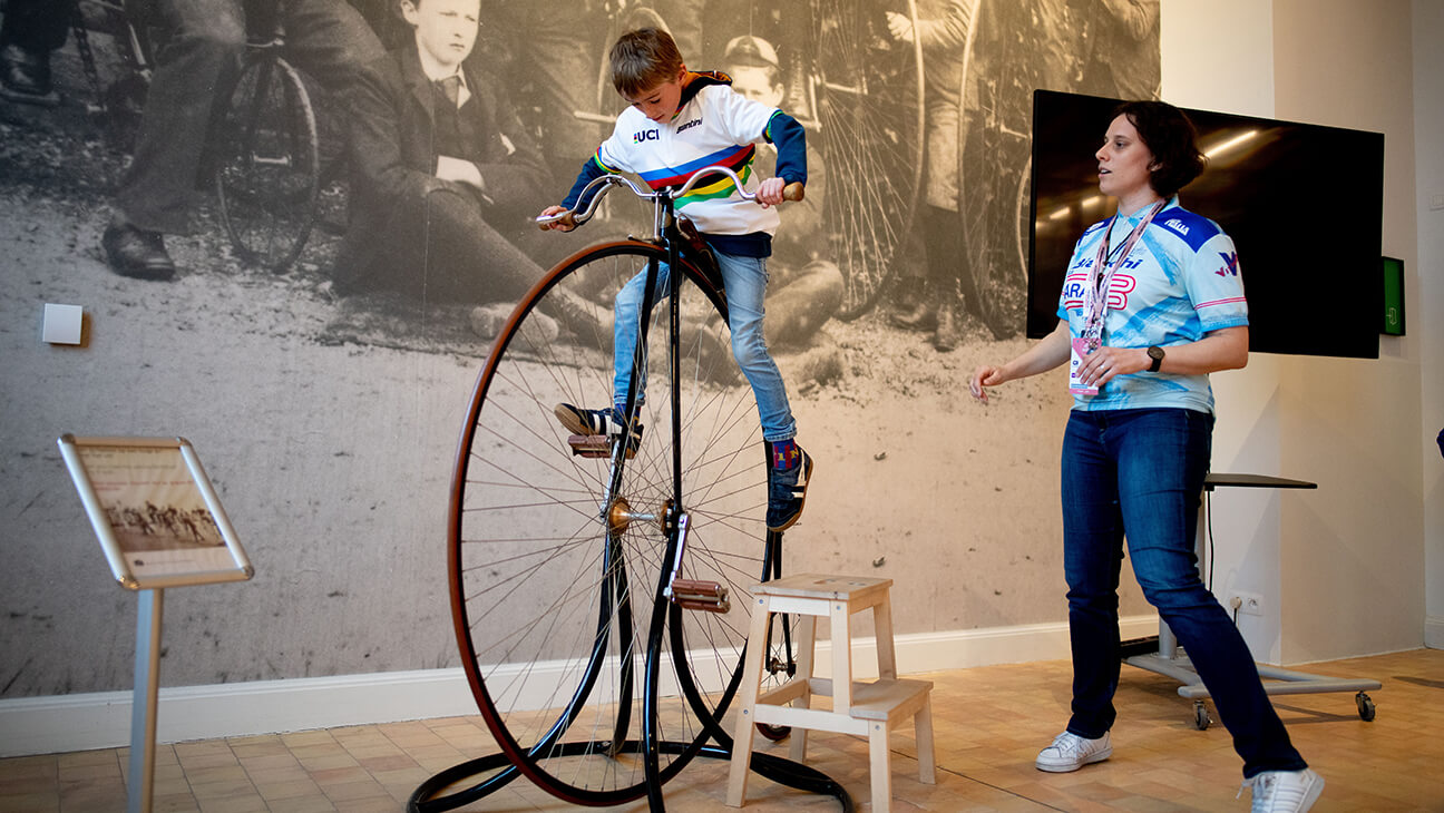 Jongen op een grote, oude fiets