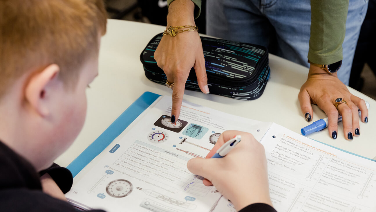 leraar wiskunde en PAV Joyce helpt leerling B-stroom met oefening in handboek