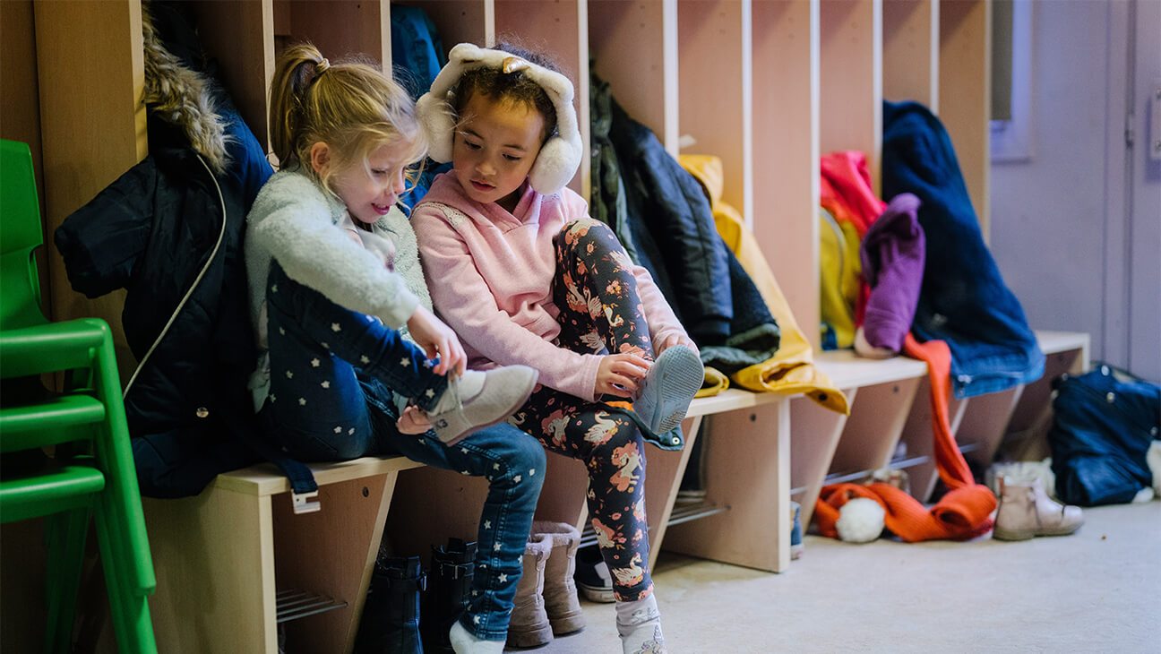 2 kinderen doen schoenen aan in de klas