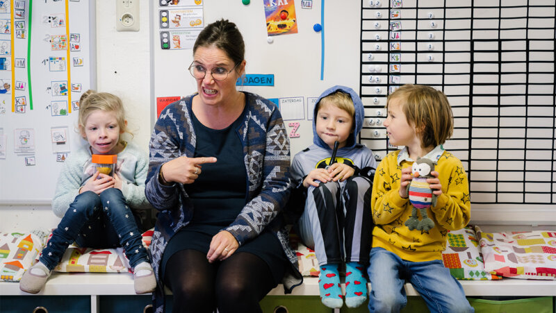 Leraar Gwenny met haar leerlingen op een bankje