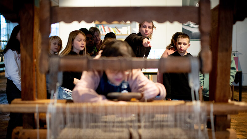 Klas bij een weefgetouw in het industriemuseum in Gent