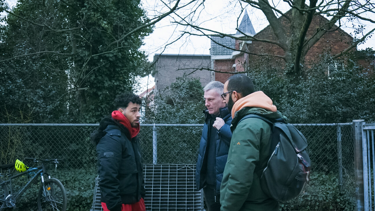 Leerlingencoördinator spreekt met leerling aan de schoolpoort