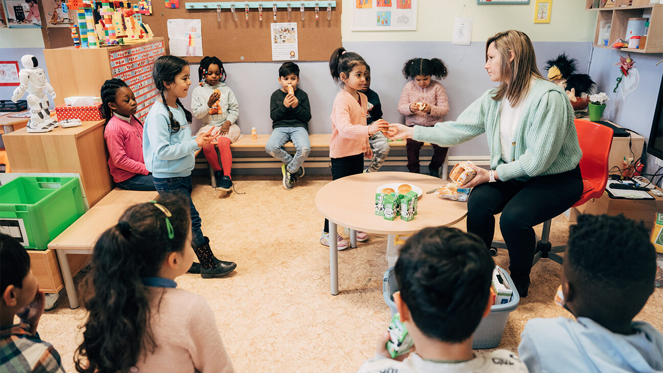 Juf deelt eten en drinken uit in de klas