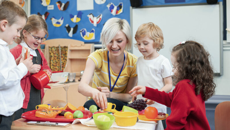 kinderen en juf spelen met plastic voeding in de klas