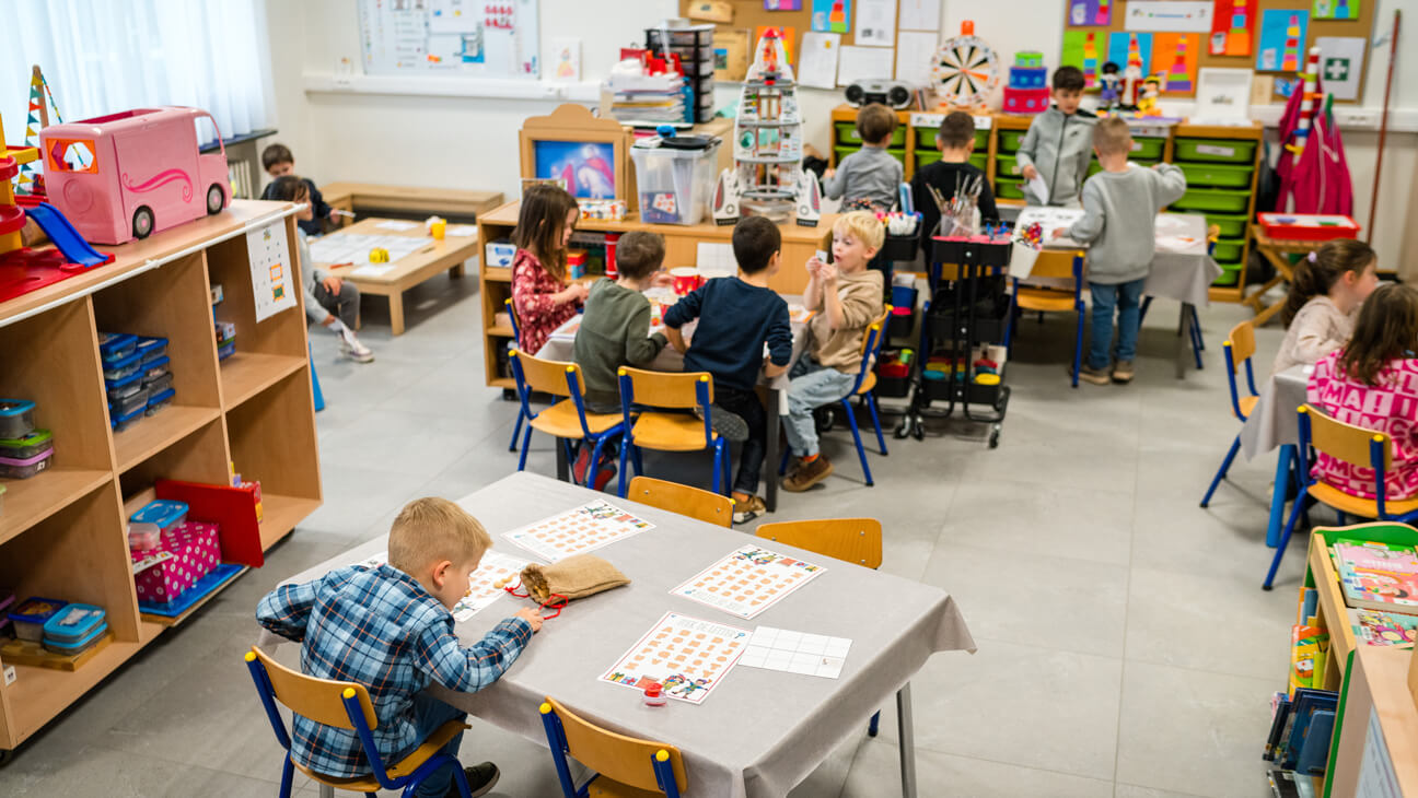 Kinderen in alle hoekjes van de klas bezig met hun speelleerbox