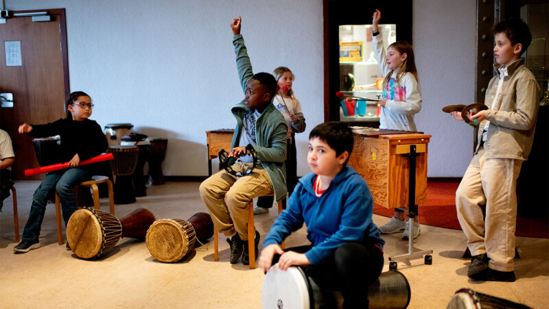 Kinderen spelen om trommels en xylofonen in het muziekinstrumentenmuseum