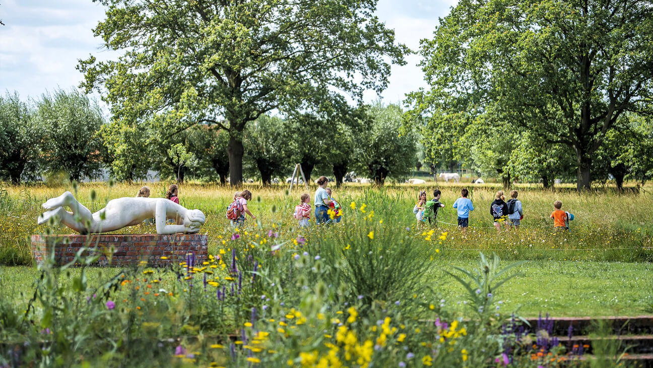 Kinderen lopen door een veld in het Permekemuseum
