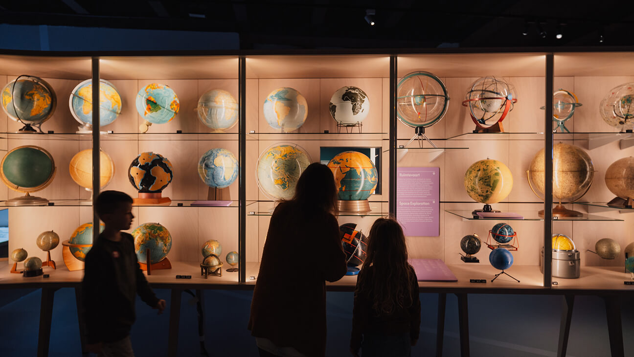 Bezoekers kijken naar verschillende wereldbollen