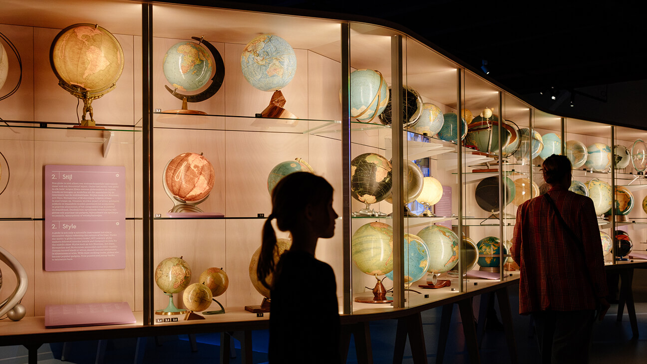 Bezoekers kijken naar verschillende wereldbollen