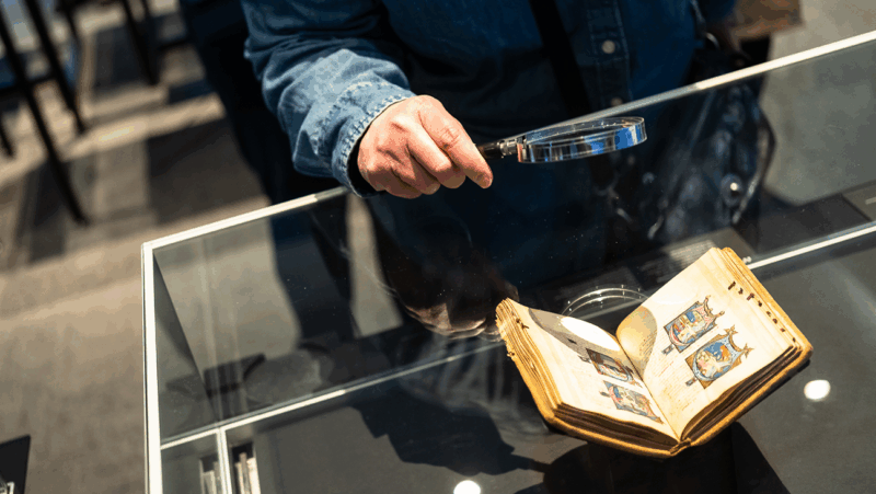 Man kijkt met vergrootglas naar boek