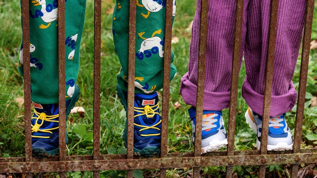 Twee kindjes bij een hek met schoenen van Schoenwinkel Hippeschoentjes