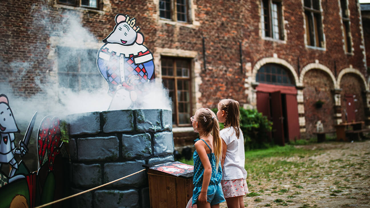2 kinderen kijken naar waterput waar rook uit komt tijdens de expo 'Ridder Muis en de kleren van Koning'