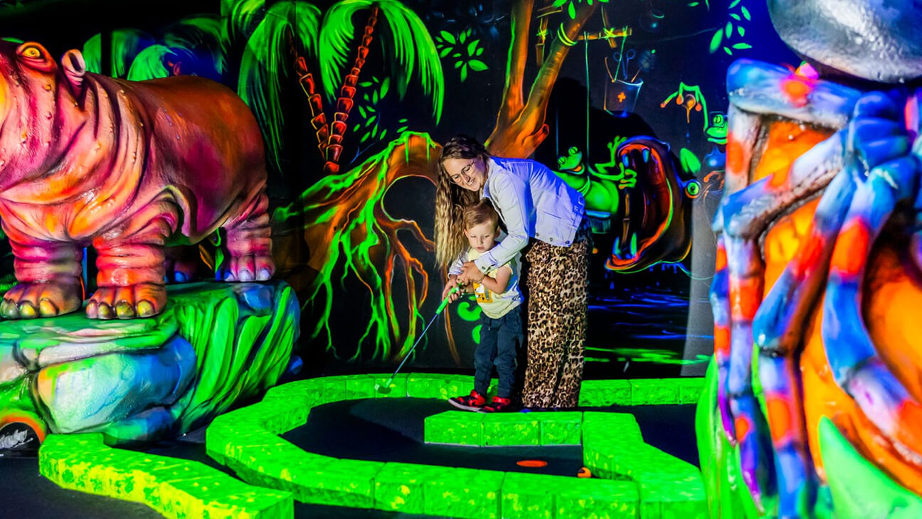 Mama en kind spelen minigolf in Jungle City