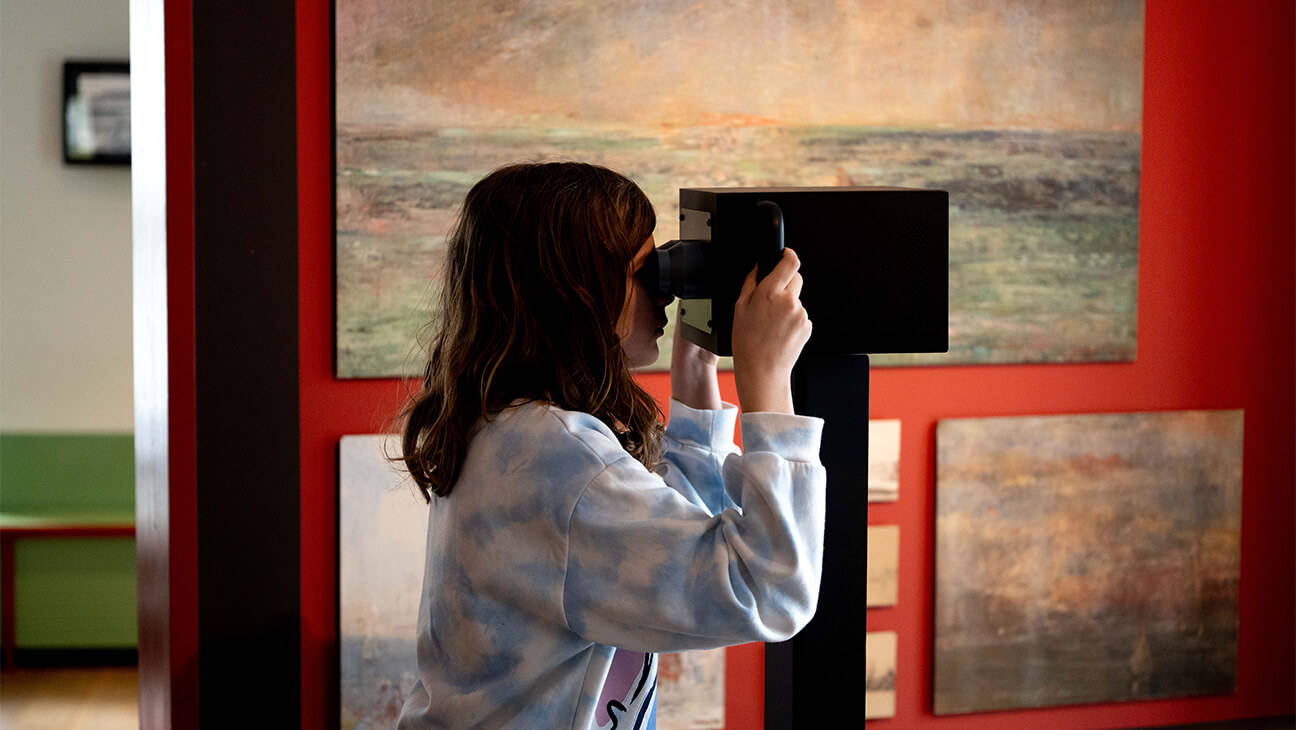 Meisje kijkt door verrekijker in het James Ensorhuis